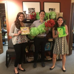 three people smiling, holding books and tissue paper caterpillaar